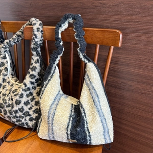 Detail of plush leopard print and striped hobo tote bags on a wooden chair