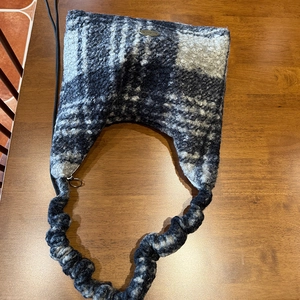 Detail of plush tote bag with grey checkered pattern and ruched handle on wood table