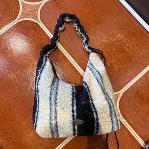 Detail of black and white striped plush tote bag with handmade metal logo and textures