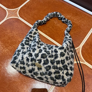 Close-up of leopard print plush tote bag with a golden metal handmade label detail