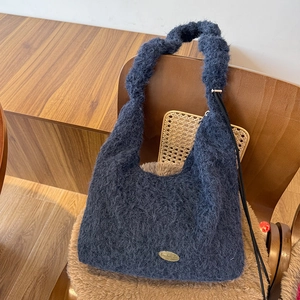 Detail of navy blue fuzzy plush shoulder bag with drawstring and handmade metal plate