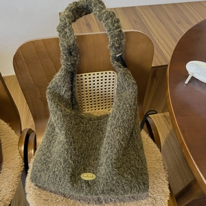Close-up of olive green plush hobo bag texture with a gold handmade metal plate detail