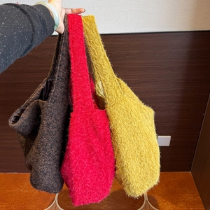 Dettaglio della texture della borsa tote in peluche nei colori marrone, rosso e giallo