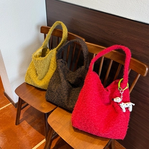 Dettaglio di borse tote in peluche giallo, marrone e rosso con ciondolo a cane
