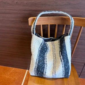 Dettaglio della borsa tote in peluche a righe che mostra la trama del tessuto su una sedia