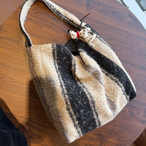 Dettaglio della borsa tote in pile a righe con portachiavi dalmata su tavolo in legno