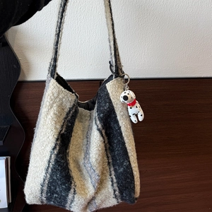 Dettaglio borsa tote a righe in peluche con ciondolo a forma di cane dalmata