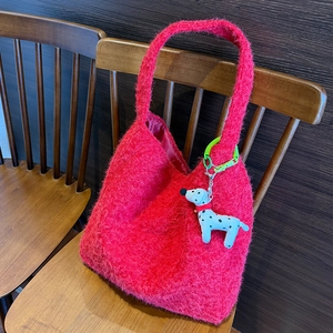 Dettaglio borsa tote in peluche rossa con ciondolo dalmata su sfondo di legno scuro