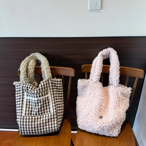 Detail of wool plush tote bags in plaid and pink faux fur on a vintage wooden chair