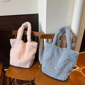 Close-up of pink and blue faux shearling tote bags on a wooden chair in cozy setting