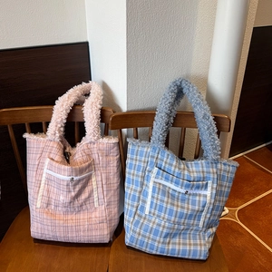 Detail view of plaid tote bags with plush fleece handles and front zipper pockets