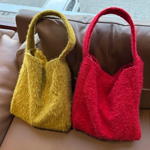 Eleganti borse tote invernali in ecopelliccia giallo senape e rosso su divano