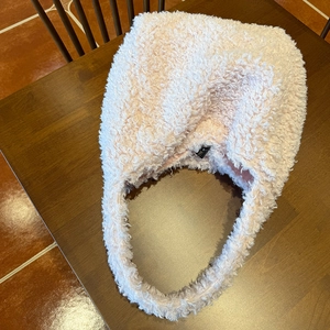 Close-up of soft faux fur tote bag in beige showing plush texture on wooden table