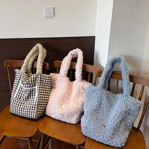 Large plush tote bags in plaid and pastel colors displayed on vintage wooden chairs