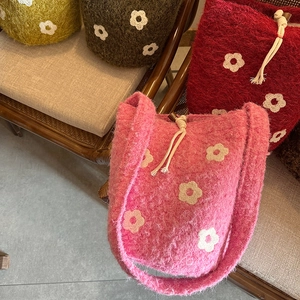 Detalle de bolso tipo cubo de felpa con bordados florales y asa tejida de alta calidad