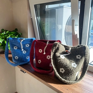 Detalle de bolsos tipo cubo de peluche con bordado floral en azul, rojo y verde oliva