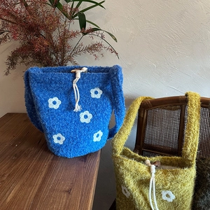 Detalle de bolsos tipo cubo de punto con bordados de flores y cierres de madera