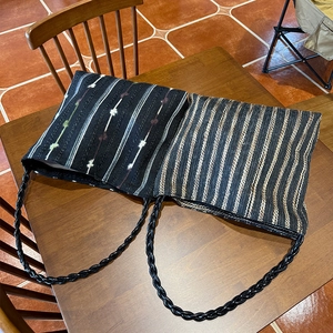 Macro detail of hand-woven striped shoulder bags with thick braided black handles