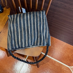Detailed knit texture of a colorful striped tote bag with braided shoulder strap