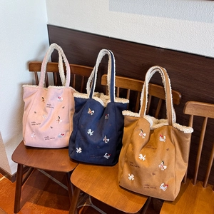 Détail de la broderie 'Hello little horse' sur des sacs fourre-tout en peluche