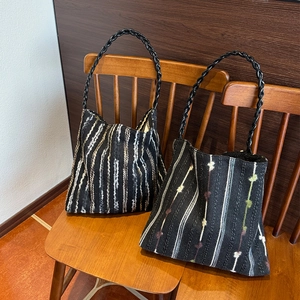 Close-up of knit tote bags with colorful stripes and weave textures on a wooden chair