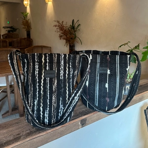 Detail of the woven texture and MODEST leather patch on the striped crossbody bucket bag