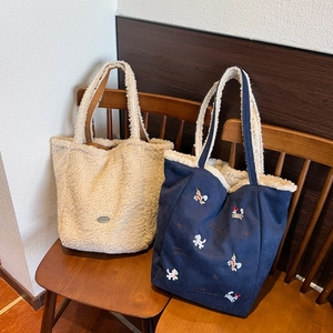 Détail de sacs cabas en peluche beige et bleu marine avec broderies d'animaux