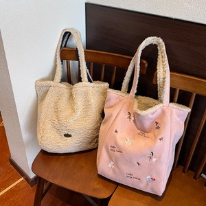 Détail de sacs fourre-tout en laine d'agneau pelucheuse avec broderie et texture douce