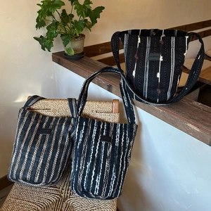 Close-up of vertical striped knitted tote bags showing woven texture and brand logo