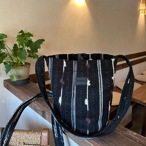 Close-up of knit fabric texture and leather logo on a striped crossbody shoulder bag