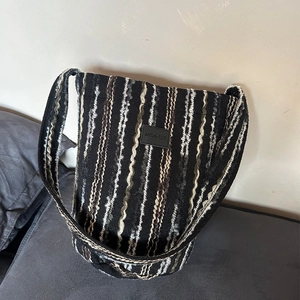 Detail shot of the chunky knit texture and Modest leather label on the striped crossbody bag