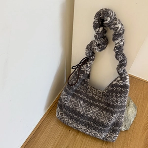 Detail of grey plush bucket bag featuring white geometric patterns and twisted handle