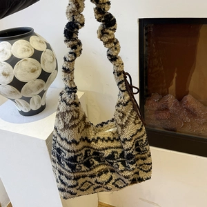 Detail of soft fleece shoulder bag with abstract black patterns and zipper closure