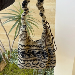 Detail of drawstring shoulder bag featuring plush fleece and patterned ethnic print