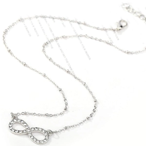 Macro shot of silver infinity pendant with white rhinestones on a delicate ball chain