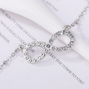 Macro shot of silver infinity pendant with micro-pave crystals on a thin delicate chain