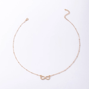 Detail of gold infinity pendant with pavé set crystals on a beaded chain necklace
