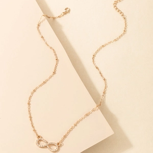 Detail of infinity pendant gold necklace with crystal inlay on a minimalist background