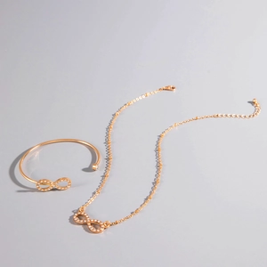Detail view of a gold infinity jewelry set with sparkling crystals on necklace and cuff