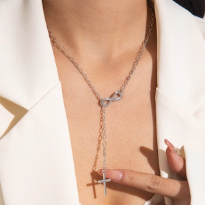 Polished silver infinity and cross lariat necklace shown on a white blazer outfit