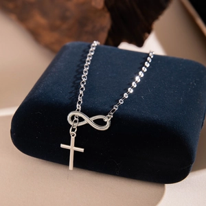 Silver infinity and cross pendant necklace displayed on a luxury navy jewelry box