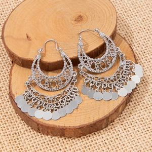 Vintage silver hollow moon earrings with metallic tassel charms on wood background