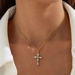 Macro detail of gold cross pendant with marquise stones worn on the collarbone
