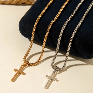 Detail of gold and silver cross necklaces displayed on velvet stands for layering