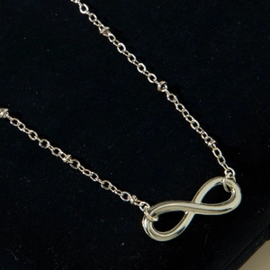Macro shot of silver infinity symbol necklace on a black velvet display background