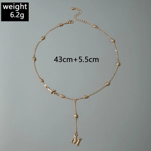 Detail of gold M initial pendant and cross necklace with adjustable lobster clasp