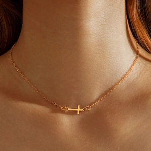 Close-up of a gold cross pendant necklace layered on neck showing fine O-chain detail