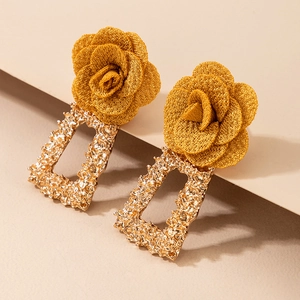 Détail de boucles d'oreilles vintage en métal doré texturé et fleurs en maille jaune