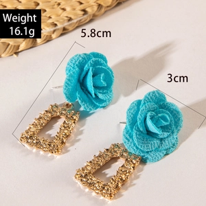 Détails de boucles d'oreilles vintage avec roses en tissu bleu et texture dorée