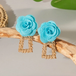 Détail de boucles d'oreilles rose bleue en tissu avec cadre géométrique doré texturé